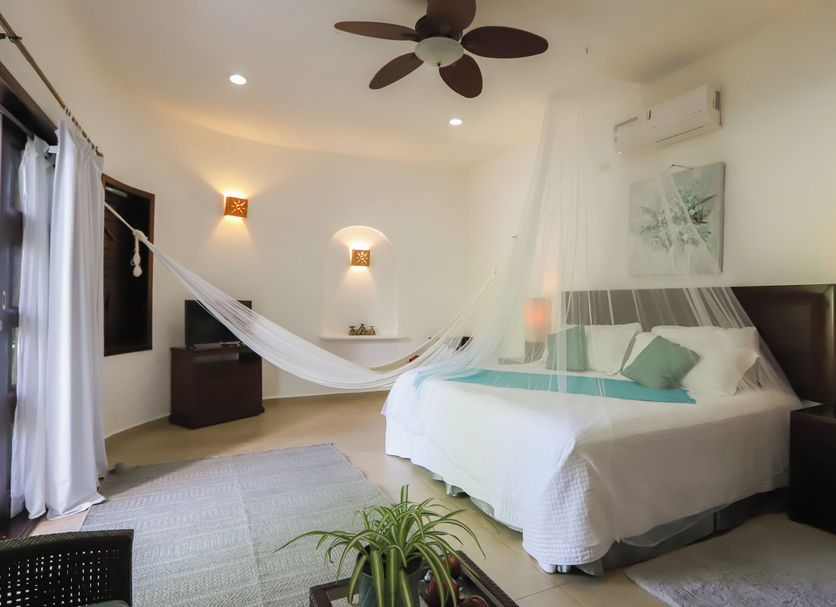 Mayan Secret Hotel Boutique in Chetumal guest room with king bed, hammock, and ceiling fan