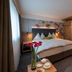 Sunstar Hotel Klosters room in Klosters-Serneus with king bed, wood wardrobe, and magenta chair