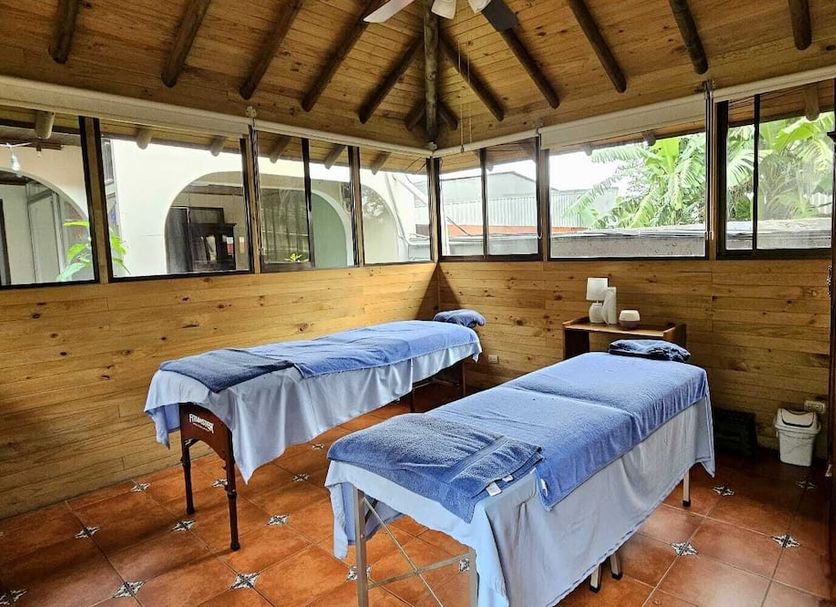 Brillasol Airport Hotel in Alajuela spa treatment room with two massage tables and wood-paneled walls