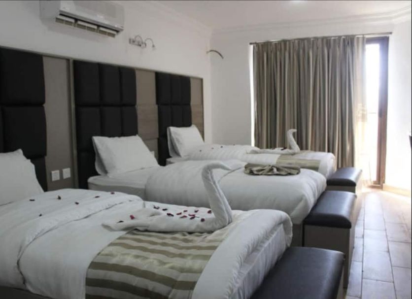 Ahla Tala Hotel in Aqaba guest room with three single beds, balcony door, and air conditioner