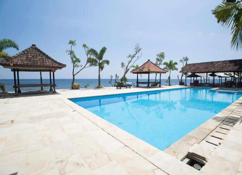 Tanjung Alam Hotel in Buleleng with a seaside pool, gazebos, palm trees, and ocean view