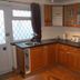 Novello Blackpool kitchen with wood cabinets, black countertops, sink, microwave and toaster