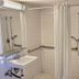 Motel 6 Coalinga East bathroom with roll-in shower, wall-mounted sink, grab bars and bench