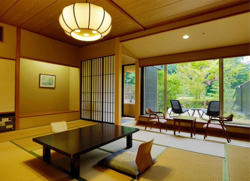 Shima Grand Hotel in Nakanojo: tatami room with low table and chairs beside a large garden view window.