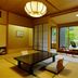 Shima Grand Hotel in Nakanojo: tatami room with low table and chairs beside a large garden view window.