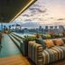 The Social Hub Barcelona Poblenou rooftop lounge with striped sofa and city skyline at sunset