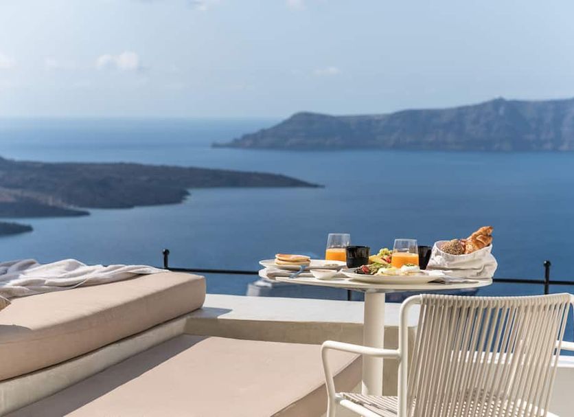 Enigma Suites Thera terrace with lounge bed, breakfast table and caldera sea view