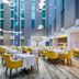 Atrium Hotel Heathrow in Hounslow dining room with yellow chairs and tall atrium windows