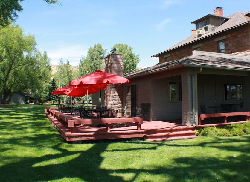 Ranch at Ucross in Clearmont with red patio umbrellas and outdoor seating beside a lodge