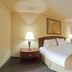 Holiday Inn Express & Suites Kerrville guest room with king bed, bedside lamps, ceiling fan and seating area.