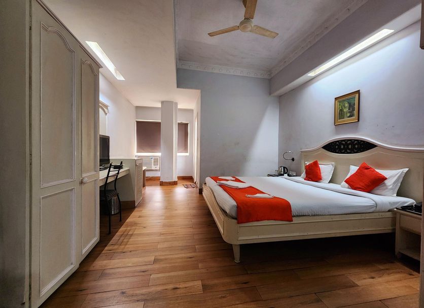 Park Palace Hotel Kolkata room with double bed, red accents, wood flooring and ceiling fan