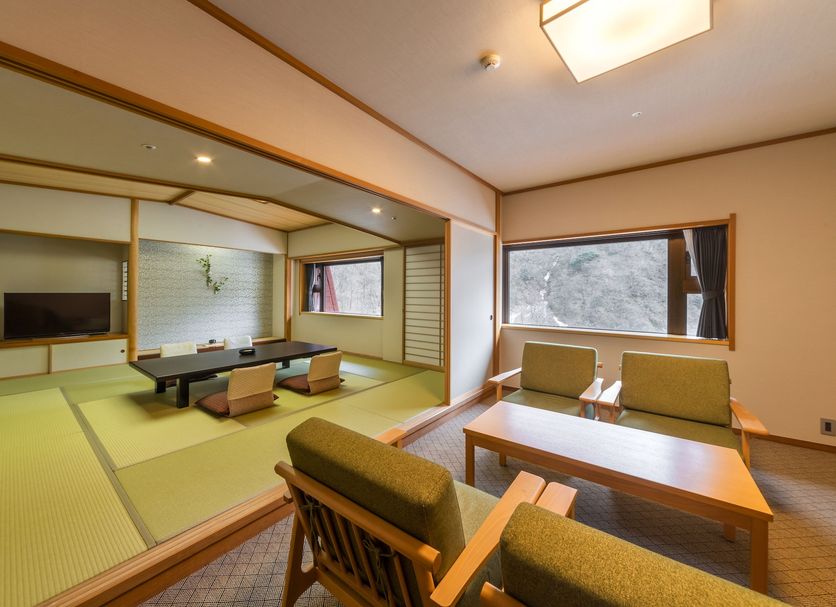Kurobe Unazuki Onsen Yamanoha in Kurobe features a tatami room with low seating and mountain-view window.