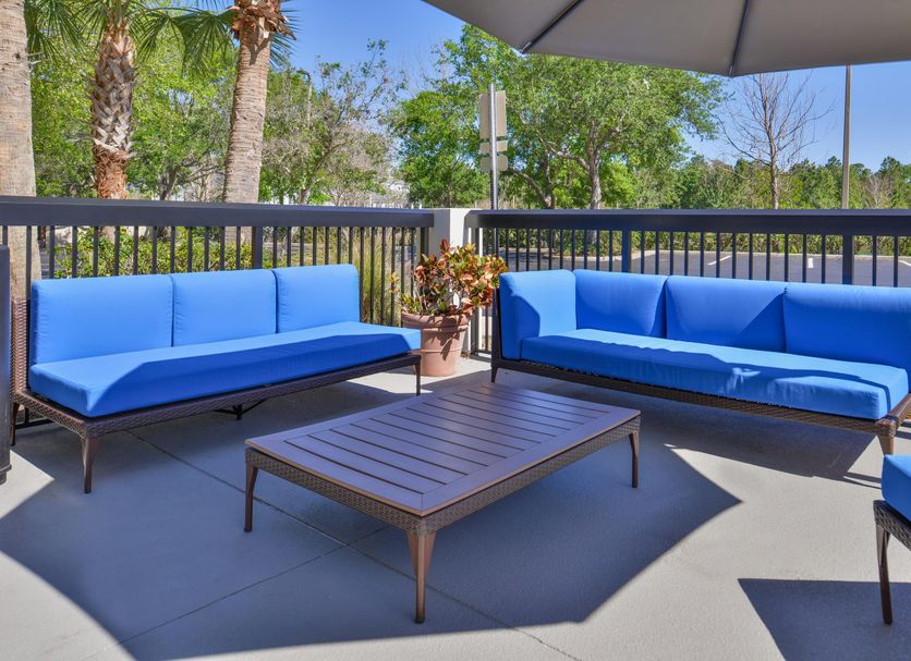 Hampton Inn Daytona/Ormond Beach patio with blue cushioned seating and umbrella, Ormond Beach