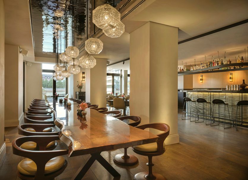 The Nikolai Hamburg lounge and bar with long dining table and pendant lights in Hamburg