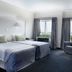 Apollo Hotel Johannesburg guest room with two twin beds, armchair, and city view through windows
