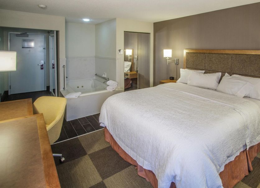 Hampton Inn South Haven guest room with king bed, sofa, desk, and soaking tub