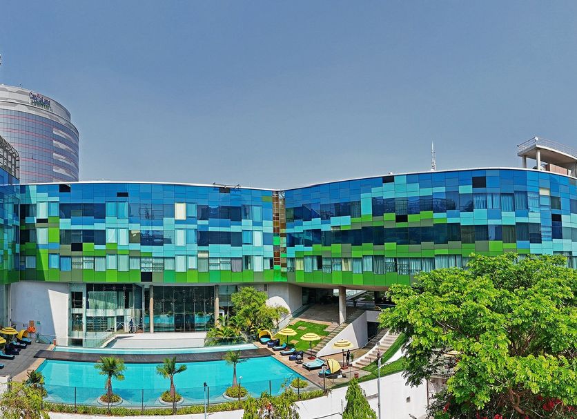 Vivanta Bengaluru, Whitefield in Bengaluru with a colorful glass exterior and outdoor pool amid greenery