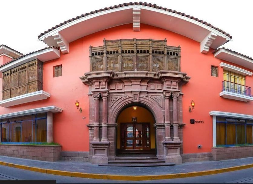 Dm Hoteles Ayacucho in Ayacucho, coral colonial-style facade with carved stone entrance and balconies
