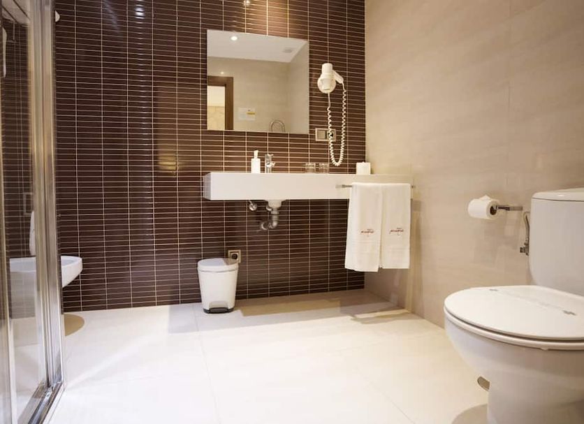 Hotel Piramide in Pontevedra bathroom with glass shower, wall-mounted sink, mirror, and toilet