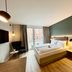 Zeitwohnhaus Suite-Hotel & Serviced Apartments in Erlangen, modern guest room with bed, balcony doors and armchair.