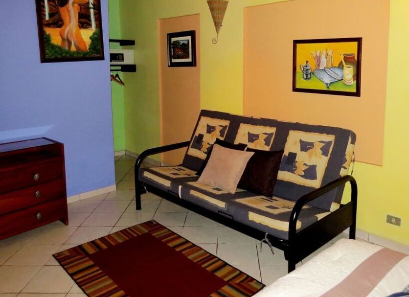 Arte Natura Boutique Hotel in La Fortuna: colorful room with sofa, wall art, and tiled floor