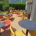 Outdoor terrace at Campanile Grenoble Sud - Seyssins with colorful tables and chairs in a garden setting