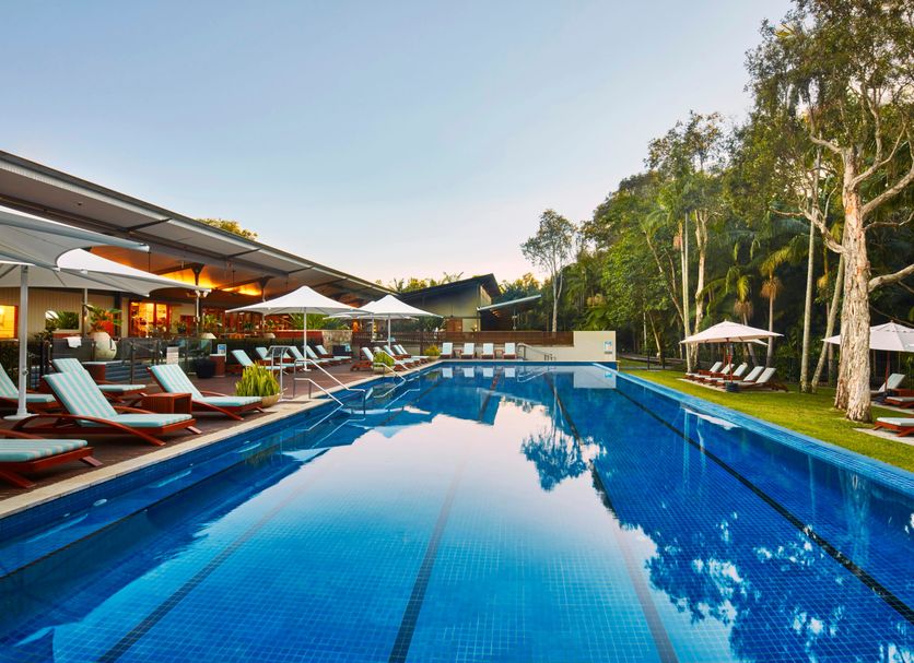 Crystalbrook Byron in Byron Bay with a long outdoor pool, sun loungers, and lush tropical surroundings