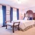 Brick Street Inn in Zionsville guest room with ornate bed, bench, desk, lamp and blue curtains