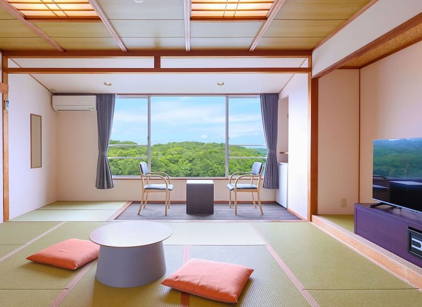 Ooedo Onsen Monogatari Premium Iseshima in Shima: tatami room with large window and green hillside view
