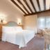 Gran Hotel Los Angeles in Getafe guest room with double bed, TV, desk and chair, and beamed ceiling