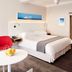 First Group Riviera Suites in Cape Town guest room with bed, red chair, white table, and kitchenette doorway