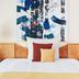 Living Hotel Großer Kurfürst in Berlin guest room with bed, abstract wall art, and bedside lamps