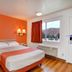 Motel 6 Twentynine Palms guest room with bed, orange accent wall, and mountain view window