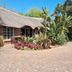 Emerald Guesthouse in Kempton Park with thatched-roof exterior, garden landscaping and paved driveway