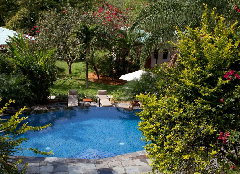 Ka'ana Resort in San Ignacio with a blue outdoor pool surrounded by lush tropical gardens and lounge chairs