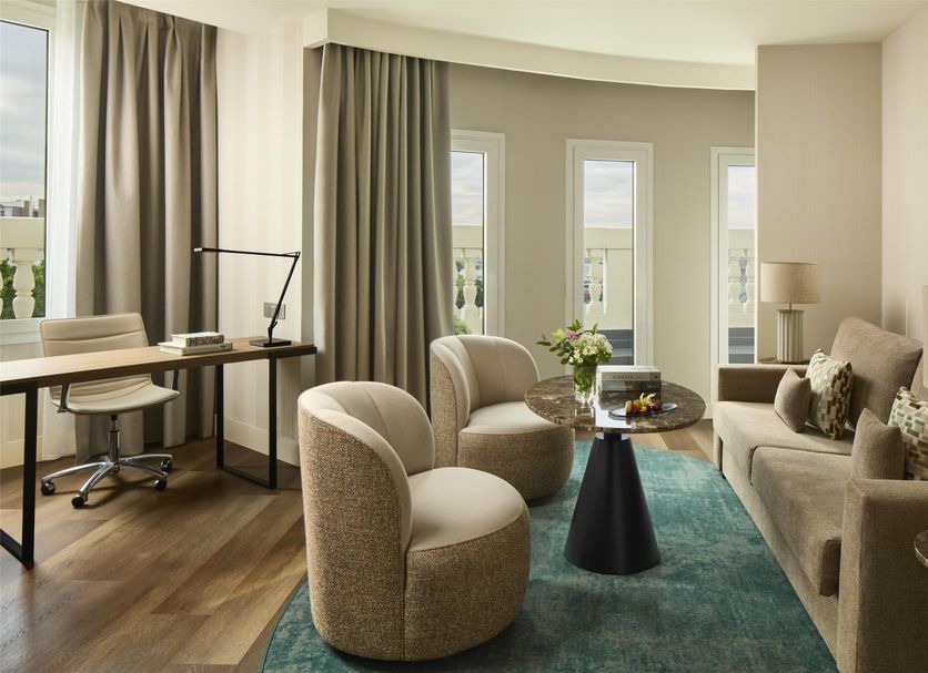 NH Madrid Nacional lounge suite with sofa, chairs, desk and tall windows in Madrid