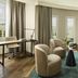 NH Madrid Nacional lounge suite with sofa, chairs, desk and tall windows in Madrid