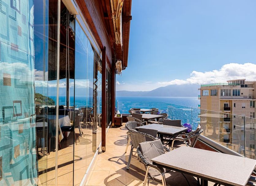 Aliko Hotel Vlorë terrace with outdoor tables and chairs overlooking the sea and mountains