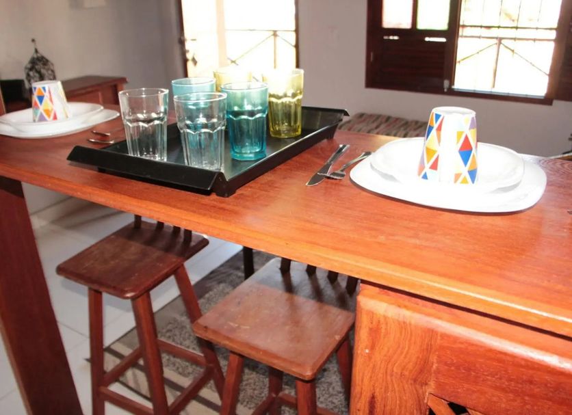 Pousada Innova in Natal dining table with stools, plates, glasses and cups in a bright room