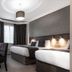 Qudos Salisbury hotel room with two beds, desk, wall-mounted TV, and window with curtains
