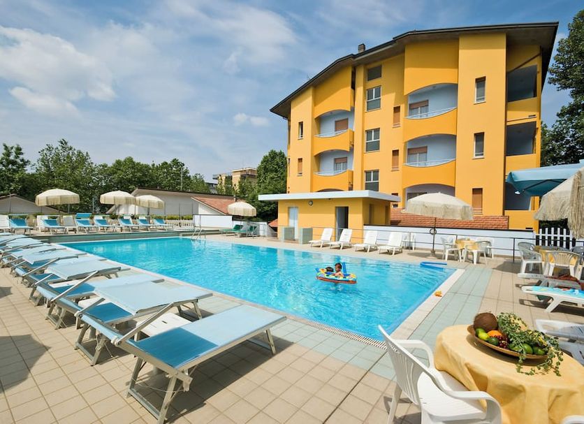 Hotel & Residence Parador in Cesenatico with outdoor pool, sun loungers, and yellow hotel facade