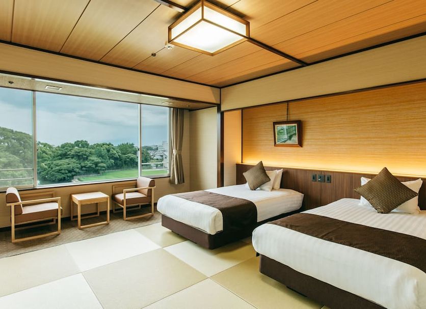 Kamenoi Hotel Yanagawa guest room with twin beds and large window overlooking lush greenery in Yanagawa