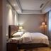 Linyi Hotel (Yimeng Road Branch) guest room with double bed, wall-mounted TV and floor lamp in Linyi