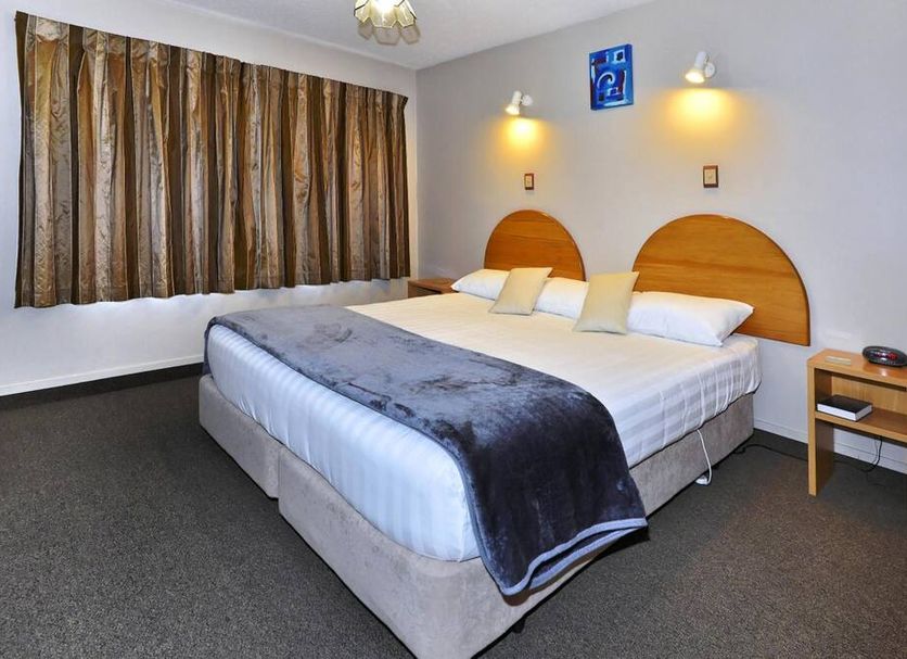 Classique Lodge Motel Christchurch guest room with double bed, bedside tables and curtained window