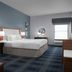 Hampton Inn Russellville guest room with king bed, blue walls, patterned carpet, and window seating area