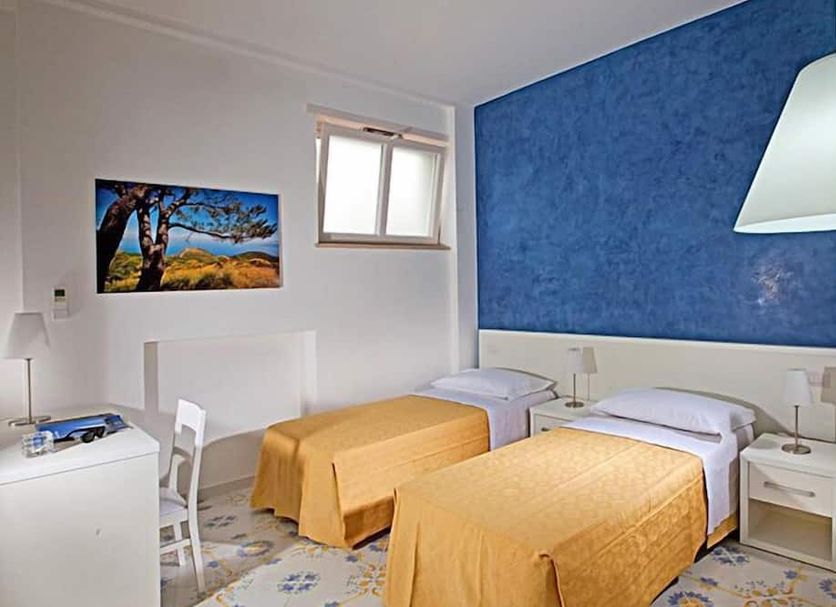San Nicola Guest House Anacapri twin room with yellow bedspreads, blue accent wall and small window