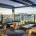 QT Auckland rooftop lounge with glass walls, city skyline views, and cushioned seating in Auckland