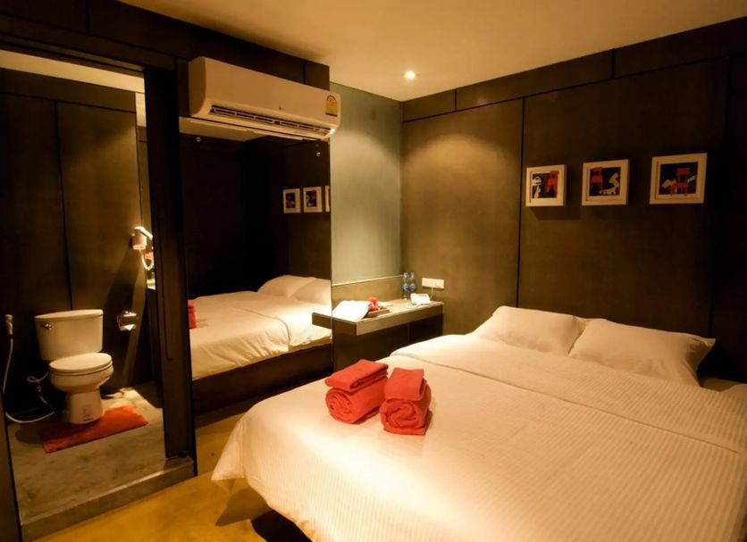 Justbeds Bangkok room with two beds, mirrored wall, and en suite bathroom visible