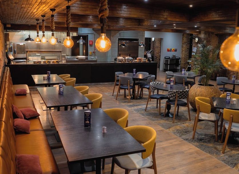a&o London Docklands Riverside restaurant lounge in London with tables, bar, and warm pendant lighting