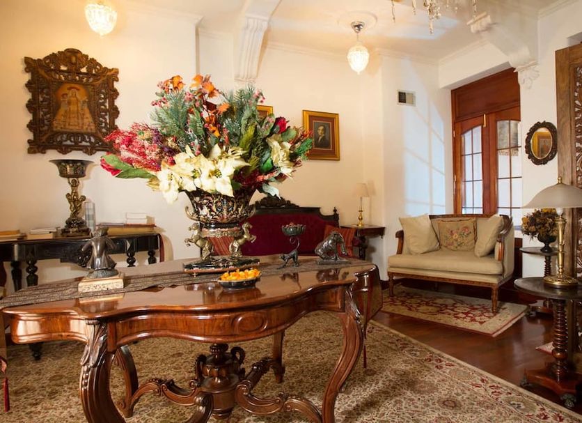 Hotel El Relicario Del Carmen Quito elegant lounge with ornate wood furniture and floral centerpiece